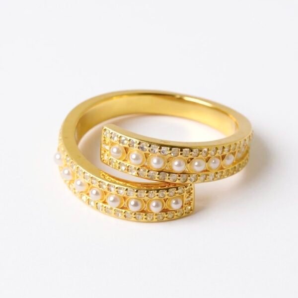 The Aurora Ring radiates refined beauty with its open-band design, delicately adorned with rows of miniature pearls and sparkling stones. Crafted in a gold-plated finish, it captures the soft glow of dawn, symbolizing hope, renewal, and timeless elegance. Its graceful curve allows the pearls to glisten like the first morning light, making it a versatile piece that elevates any look, whether worn solo or paired with your favorite Bella Pia jewels.