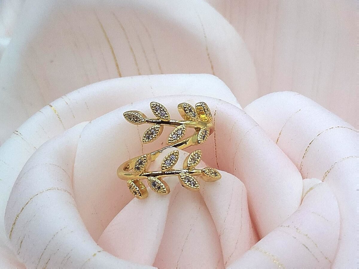 Gold wrap ring designed with two branches of crystal-studded leaves.