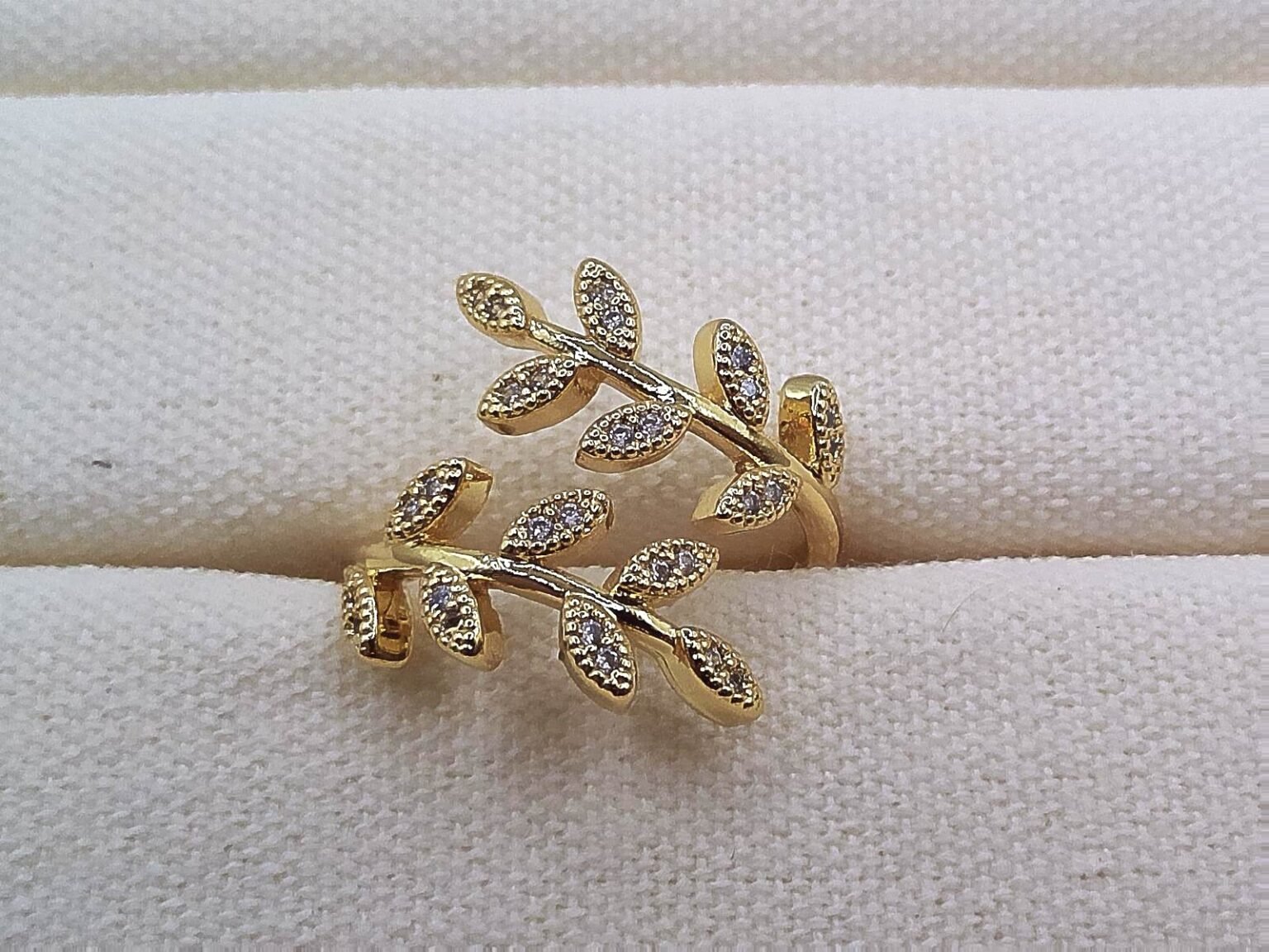 Gold wrap ring designed with two branches of crystal-studded leaves.