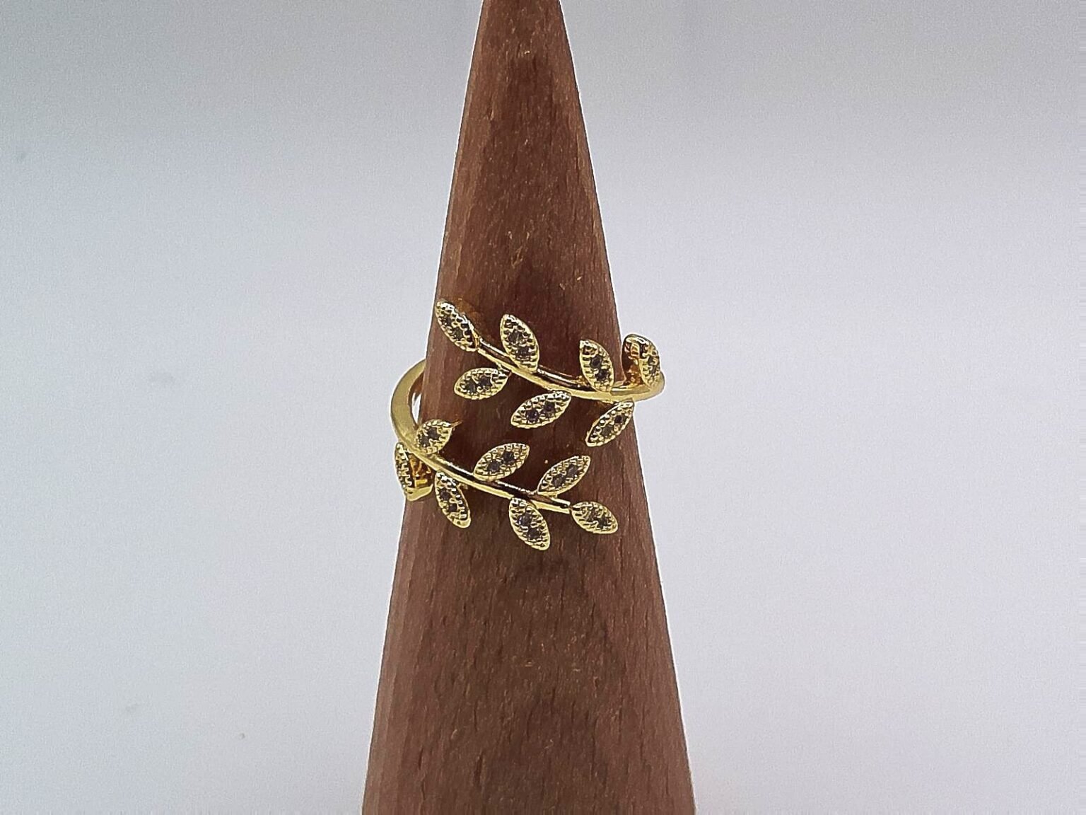 Gold wrap ring designed with two branches of crystal-studded leaves.