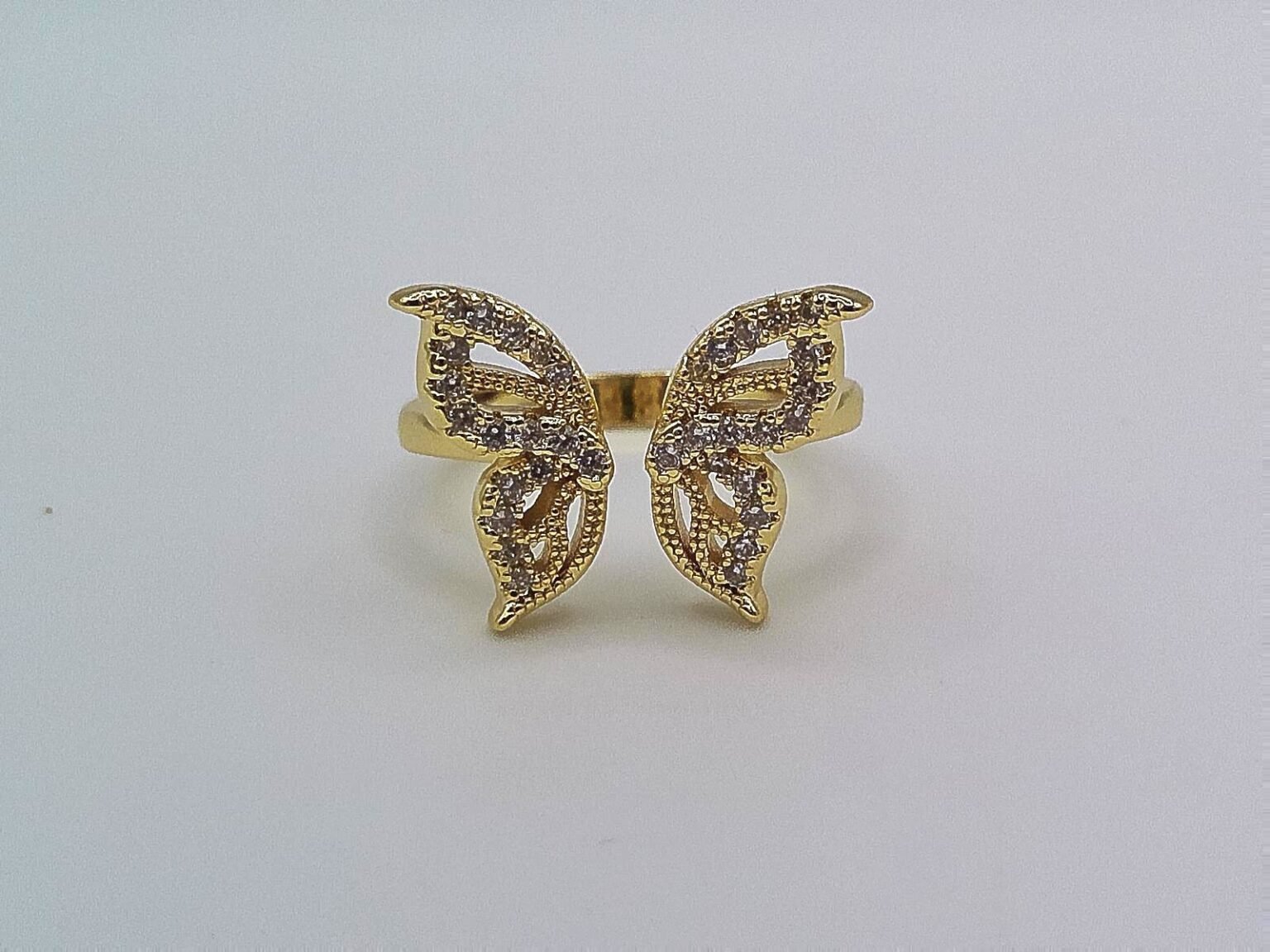 Gold ring shaped like a butterfly with wings encrusted in crystals.