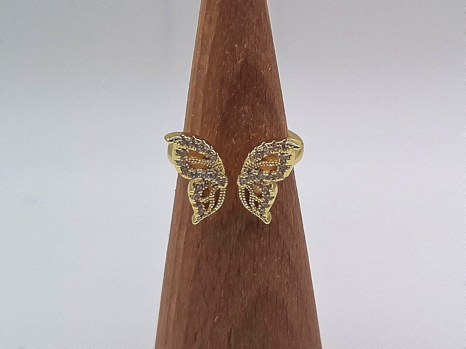 Gold ring shaped like a butterfly with wings encrusted in crystals.