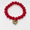 The Angalia Cuore bracelet is handcrafted with luminous red facted crystal beads, finished with a gleaming gold-plated heart charm etched in leopard detail. A radiant symbol of fierce love and fearless style, this bracelet is designed to catch the light and elevate any look. Whether worn solo as a statement piece or stacked for extra drama, Angalia Cuore is elegance with an edge. This bracelet looks beautiful on its own but truly shines when stacked with the classic black beaded bracelet. The bold red and gold heart charm create a striking contrast when paired with black, making it perfect for day-to-night elegance.