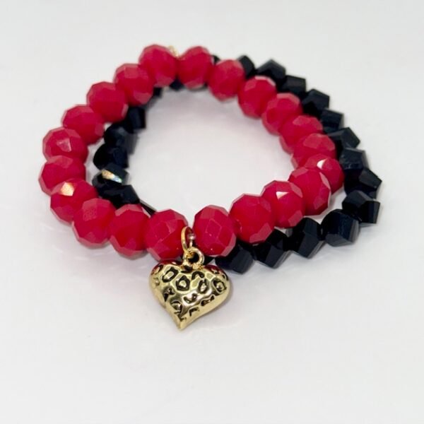The Angalia Cuore bracelet is handcrafted with luminous red facted crystal beads, finished with a gleaming gold-plated heart charm etched in leopard detail. A radiant symbol of fierce love and fearless style, this bracelet is designed to catch the light and elevate any look. Whether worn solo as a statement piece or stacked for extra drama, Angalia Cuore is elegance with an edge. This bracelet looks beautiful on its own but truly shines when stacked with the classic black beaded bracelet. The bold red and gold heart charm create a striking contrast when paired with black, making it perfect for day-to-night elegance.