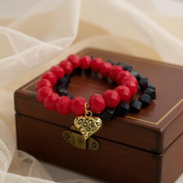 The Angalia Cuore bracelet is handcrafted with luminous red facted crystal beads, finished with a gleaming gold-plated heart charm etched in leopard detail. A radiant symbol of fierce love and fearless style, this bracelet is designed to catch the light and elevate any look. Whether worn solo as a statement piece or stacked for extra drama, Angalia Cuore is elegance with an edge. This bracelet looks beautiful on its own but truly shines when stacked with the classic black beaded bracelet. The bold red and gold heart charm create a striking contrast when paired with black, making it perfect for day-to-night elegance.