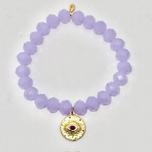 The Occhio Celeste bracelet radiates mystical beauty with faceted lavender crystals that capture light in every movement. At the heart of the bracelet hangs a gold-plated protective eye medallion with a radiant ruby-colored center, symbolizing clarity, intuition, and divine guidance. Whether worn solo for a touch of celestial elegance or stacked for bold expression, this bracelet serves as both a style statement and a talisman of light.