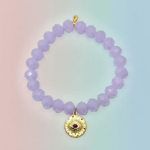 The Occhio Celeste bracelet radiates mystical beauty with faceted lavender crystals that capture light in every movement. At the heart of the bracelet hangs a gold-plated protective eye medallion with a radiant ruby-colored center, symbolizing clarity, intuition, and divine guidance. Whether worn solo for a touch of celestial elegance or stacked for bold expression, this bracelet serves as both a style statement and a talisman of light.