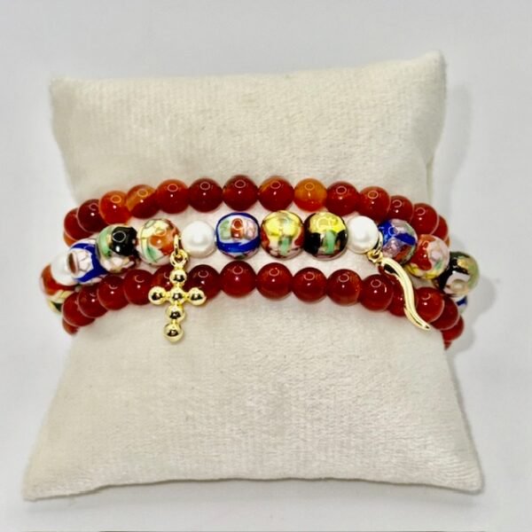 The Fede e Fortuna bracelet captures the essence of Italian tradition and protection. Crafted with hand-painted cloisonné beads in vibrant hues, accented with luminous pearls, and finished with symbolic gold-plated charms — a cross for faith and a cornicello for luck — this bracelet is more than an accessory; it’s a talisman of beauty, meaning, and heritage. Perfect for those who embrace both spiritual strength and good fortune in their journey. Wear it on its own as a statement of faith and fortune, or stack it with the deep red stone beaded bracelet to amplify its bold, passionate energy and create a truly striking layered look.