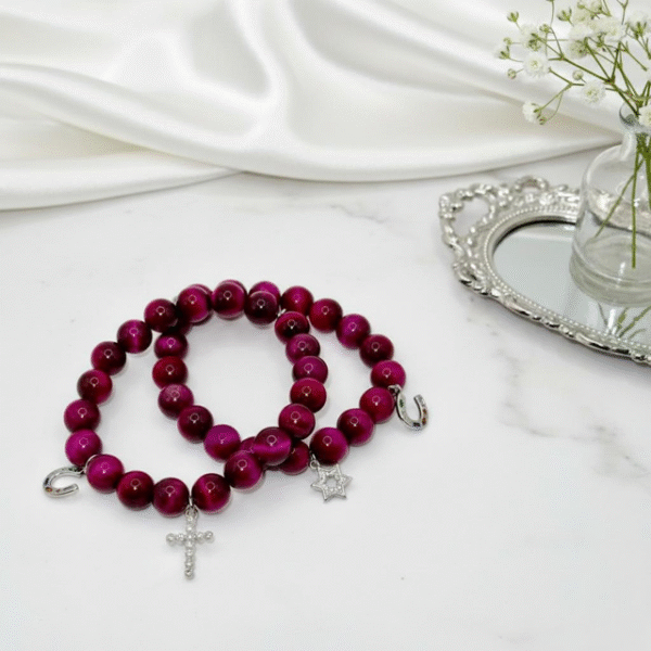 Celebrate heritage, unity, and strength with our Star of David Bracelet. Featuring vibrant magenta stone beads, this bracelet is adorned with a silver sparkling Star of David charm and a silver horseshoe for luck. A meaningful piece that intertwines tradition with contemporary elegance, it offers both protection and beauty in every detail. Wear it solo as a bold expression of faith, or stack it with the green jade bracelet for a striking contrast that symbolizes balance, renewal, and protection.