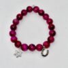 Celebrate heritage, unity, and strength with our Star of David Bracelet. Featuring vibrant magenta stone beads, this bracelet is adorned with a silver sparkling Star of David charm and a silver horseshoe for luck. A meaningful piece that intertwines tradition with contemporary elegance, it offers both protection and beauty in every detail. Wear it solo as a bold expression of faith, or stack it with the green jade bracelet for a striking contrast that symbolizes balance, renewal, and protection.