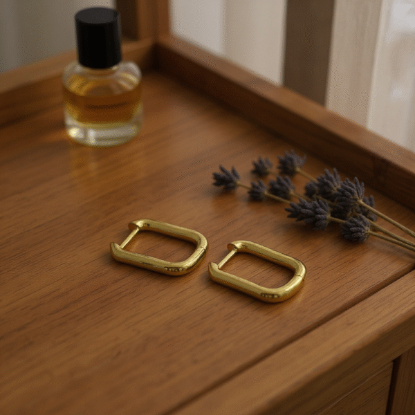 The Oro Puro earrings embody sleek sophistication with their minimalist rectangular hoop silhouette in high-polished gold-plated finish. Designed for those who love understated elegance, these versatile earrings transition seamlessly from day to night, adding a refined edge to any look. Their lightweight design ensures comfort, while their timeless finish makes them a staple piece for your jewelry collection.