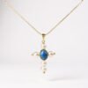 The Marina Necklace is a luminous symbol of faith and devotion. Designed in the shape of a cross, it features radiant pearls delicately balanced with a striking blue cabochon at its center, representing clarity and divine light. The reverse side is graced with a depiction of the Virgin Mary, offering protection and blessing to its wearer. A timeless piece that beautifully bridges tradition and elegance, this necklace is a keepsake meant to inspire strength and serenity.
