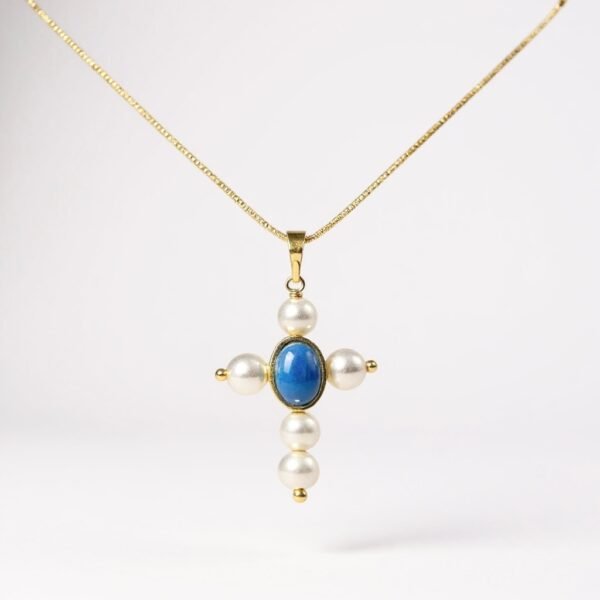 The Marina Necklace is a luminous symbol of faith and devotion. Designed in the shape of a cross, it features radiant pearls delicately balanced with a striking blue cabochon at its center, representing clarity and divine light. The reverse side is graced with a depiction of the Virgin Mary, offering protection and blessing to its wearer. A timeless piece that beautifully bridges tradition and elegance, this necklace is a keepsake meant to inspire strength and serenity.