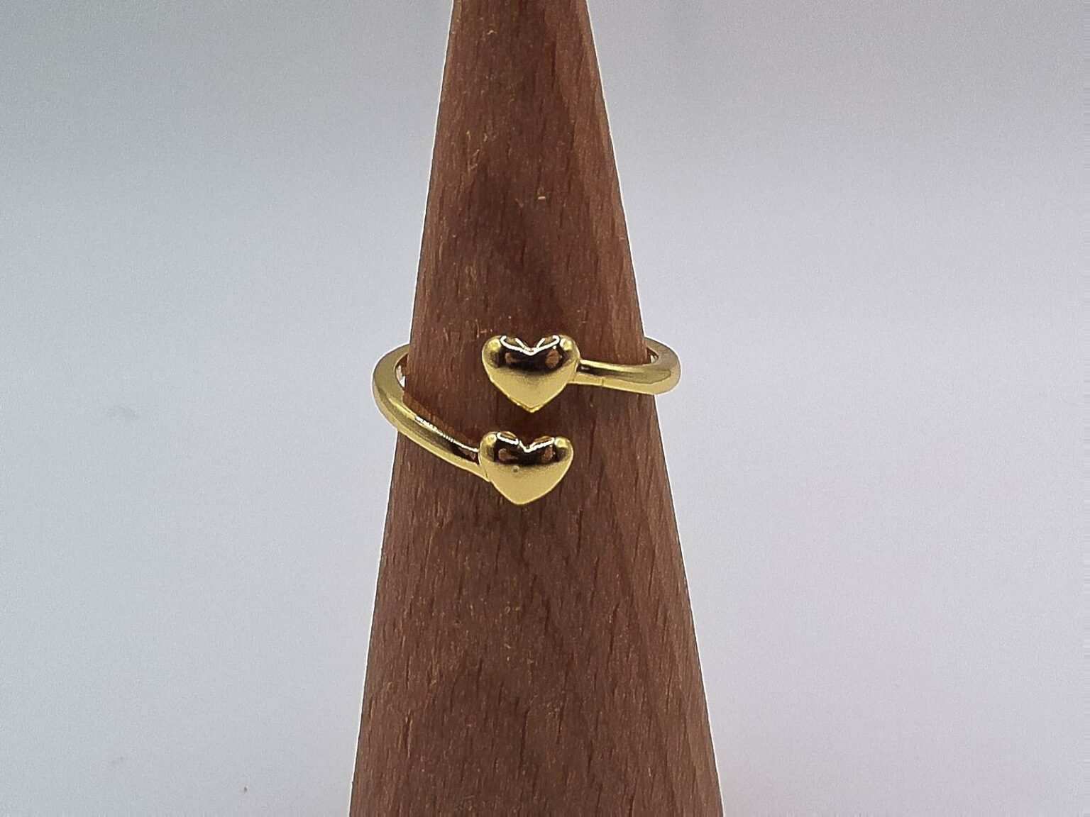 Gold open band ring with two polished heart-shaped ends facing each other.