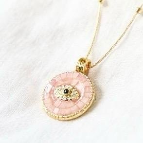 The Occhio Rosa and Occhio Bianco necklaces combine timeless tradition with modern elegance. Handcrafted with shimmering mother-of-pearl mosaics in soft blush pink or luminous white, each pendant features a sapphire-blue centerpiece surrounded by sparkling crystals — symbolizing the ancient talisman of the “evil eye.” Set in gold-plated detailing, these pendants are not only radiant accessories but also protective charms, believed to ward off negative energy while elevating any look.