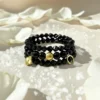 The Fortuna Nera bracelet is a striking symbol of fortune, strength, and style. Designed with smooth black onyx beads, it features radiant gold-plated charms — a delicate quatrefoil for luck, a textured orb for resilience, and a horseshoe for prosperity. Together, they create a talisman that’s both meaningful and fashion-forward. Versatile enough to wear from day to night, Fortuna Nera adds a touch of bold sophistication to any look. Whether stacked with other pieces or worn solo, it’s a timeless reminder that luck favors the bold.