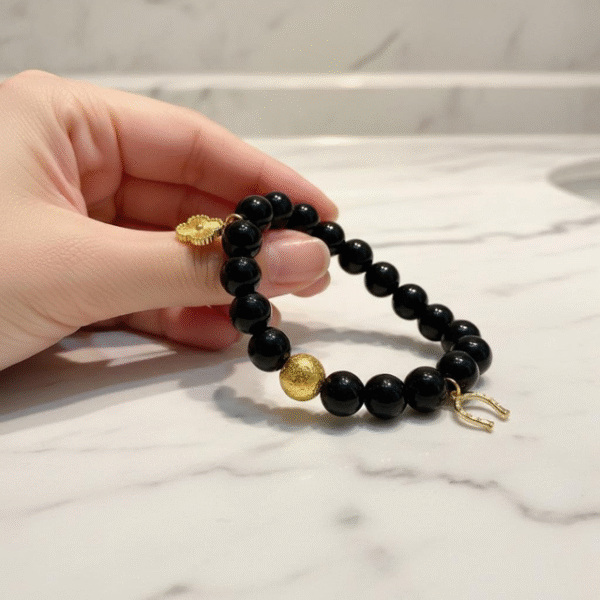 The Fortuna Nera bracelet is a striking symbol of fortune, strength, and style. Designed with smooth black onyx beads, it features radiant gold-plated charms — a delicate quatrefoil for luck, a textured orb for resilience, and a horseshoe for prosperity. Together, they create a talisman that’s both meaningful and fashion-forward. Versatile enough to wear from day to night, Fortuna Nera adds a touch of bold sophistication to any look. Whether stacked with other pieces or worn solo, it’s a timeless reminder that luck favors the bold.