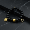 The Fortuna Nera bracelet is a striking symbol of fortune, strength, and style. Designed with smooth black onyx beads, it features radiant gold-plated charms — a delicate quatrefoil for luck, a textured orb for resilience, and a horseshoe for prosperity. Together, they create a talisman that’s both meaningful and fashion-forward. Versatile enough to wear from day to night, Fortuna Nera adds a touch of bold sophistication to any look. Whether stacked with other pieces or worn solo, it’s a timeless reminder that luck favors the bold.