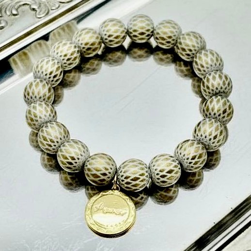 The Amore di Bellezza Bracelet celebrates the timeless bond between love and beauty. Designed with delicately patterned golden-gray beads and finished with a radiant gold-plated medallion engraved with Amor, this bracelet is a sophisticated symbol of affection and grace. A meaningful piece to wear close to your heart or gift to someone special.