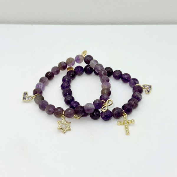 The Fede di Carolyn bracelet is a celebration of devotion, love, and lifelong friendship. Handcrafted with faceted amethyst stones, each bead carries calming and spiritual energy, symbolizing peace, clarity, and strength. The design is completed with three meaningful charms: A sparkling gold-plated cross framed with crystals, representing unwavering faith, a delicate light amethyst heart charm set in gold-plating, symbolizing pure love and compassion, and a gold-plated infinity symbol for eternity. This bracelet is a timeless reminder of unbreakable bonds and cherished connections.