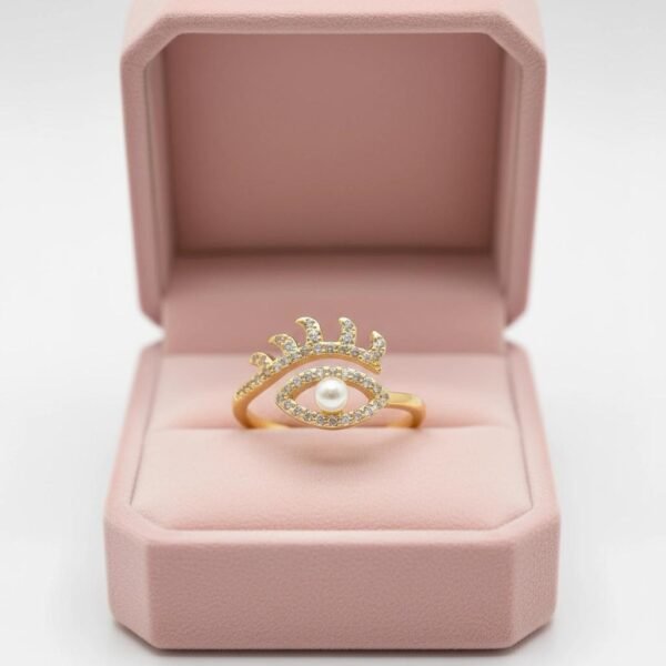The Occhio di Perla Ring is a striking fusion of symbolism and sophistication. Crafted in luminous gold plating, this captivating design features an eye-shaped silhouette lined with sparkling pavé crystals, crowned by delicate lashes that shimmer with light. At the center rests a radiant pearl, symbolizing wisdom, clarity, and protection. Inspired by the ancient talisman of the “all-seeing eye,” this ring offers both fashion-forward appeal and a touch of spiritual meaning—perfect for those who embrace bold style with intention. Its adjustable band ensures a comfortable fit, making it as versatile as it is stunning. Whether worn as a statement piece or stacked with other Bella Pia favorites, the Occhio di Perla embodies protection, power, and timeless beauty.