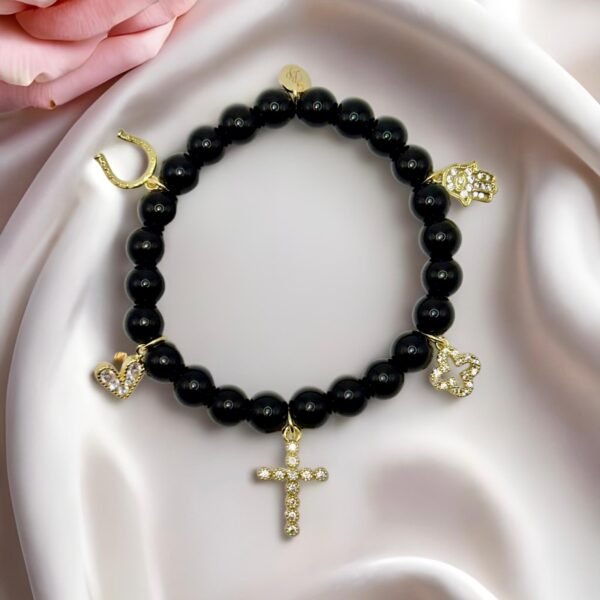 Step into protection and style with the Ginevra’s Amuleto Bracelet, a striking piece crafted with sleek black beads and adorned with radiant gold-plated charms. Featuring meaningful symbols—such as the cross, Star of David, heart, Hamsa hand, clover, and horseshoe—this bracelet celebrates spirituality, luck, and love all in one. Whether worn daily as a personal talisman or styled as a bold fashion statement, Ginevra’s Amuleto Bracelet is designed to keep positivity and elegance close to your wrist. A versatile piece for the woman who embraces both faith and fashion.