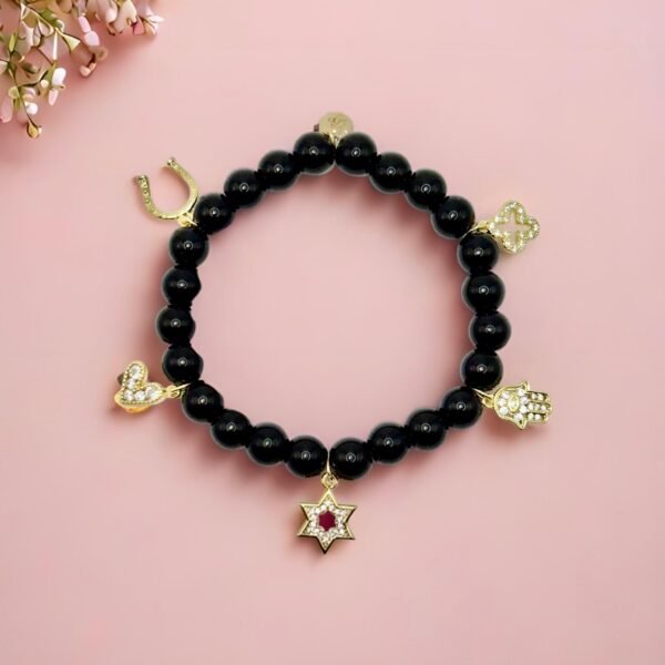 Step into protection and style with the Ginevra’s Amuleto Bracelet, a striking piece crafted with sleek black beads and adorned with radiant gold-plated charms. Featuring meaningful symbols—such as the cross, Star of David, heart, Hamsa hand, clover, and horseshoe—this bracelet celebrates spirituality, luck, and love all in one. Whether worn daily as a personal talisman or styled as a bold fashion statement, Ginevra’s Amuleto Bracelet is designed to keep positivity and elegance close to your wrist. A versatile piece for the woman who embraces both faith and fashion.