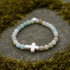 The Verde Serenità Bracelet is a calming symbol of faith and balance, handcrafted with soothing natural Amazonite stones. Known for their connection to emotional peace and inner harmony, these serene blue-green stones are beautifully paired with a white stone cross centerpiece—representing faith, guidance, and spiritual strength. Designed for both men and women, this bracelet embraces a minimalist earthy style that blends easily with everyday wear while holding a deeper meaning close to the heart. Whether worn alone or layered, it serves as a daily reminder of hope, purpose, and spiritual grounding.