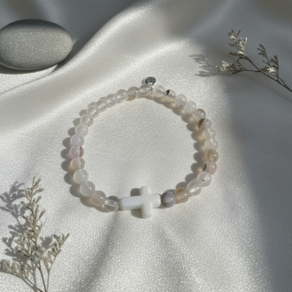 The Serenity Cross Bracelet is a minimalist expression of faith and inner peace. Handcrafted with smooth white agate gemstones, this bracelet embodies balance, grounding, and calm energy. At its center rests a sleek white cross bead, symbolizing guidance, hope, and divine protection. Its soft neutral palette makes it a beautiful and versatile accessory for both men and women, perfect for everyday wear, prayer, or meaningful gifting. Whether worn alone or stacked, it carries a message close to the heart—simple, spiritual, and sincere.