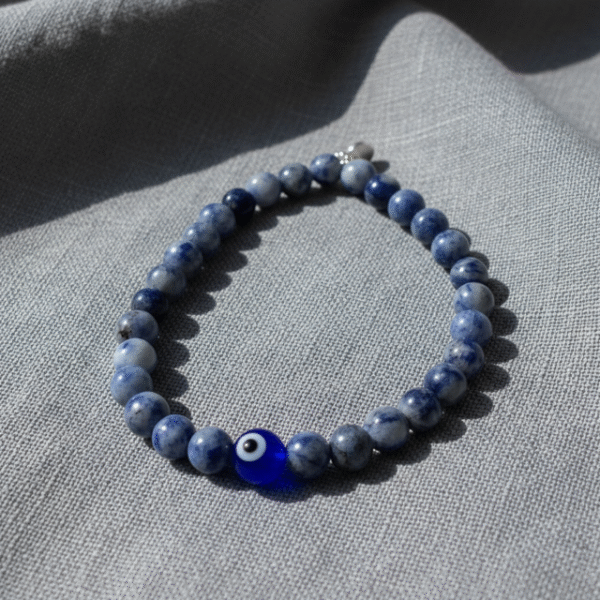 Discover effortless protection with the Azzuro Guard Bracelet—a modern take on ancient symbolism. Handcrafted with deep sapphire-blue sodalite stones, this bracelet represents clarity, intuition, and emotional balance. At its heart is the striking blue evil eye bead, a timeless symbol believed to shield against negativity and invite peace and good fortune. Versatile and powerful, this unisex bracelet transitions seamlessly from casual weekends to everyday wear. Whether worn alone or stacked, it’s a bold reminder to move through life with confidence and purpose.
