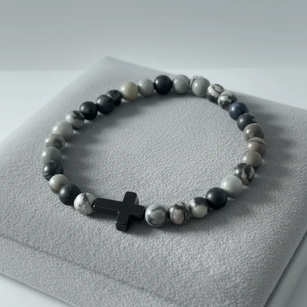 Discover refined faith with the Pietra di Fede bracelet. Designed for the modern man, this piece blends natural stone beads in bold shades of black, grey, and earthy tones with a sleek cross centerpiece. Each bead is uniquely patterned, making every bracelet one of a kind. Wear it as a daily reminder of direction, purpose, and grounded strength. Built on durable stretch cord for all-day comfort—casual enough for everyday wear, meaningful enough for moments that matter.