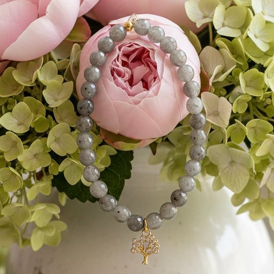 Graceful, grounding, and filled with meaning — the Albero di Luce bracelet is a symbol of growth, strength, and new beginnings. Handcrafted with shimmering natural grey labradorite beads, it's adorned with a delicate gold Tree of Life charm that celebrates connection to nature and inner balance. The soft glow of each bead reflects subtle flashes of light—gentle reminders to stay rooted while reaching toward your dreams. Elegant enough for special occasions and meaningful enough for everyday wear, this bracelet is a modern talisman for the soul.