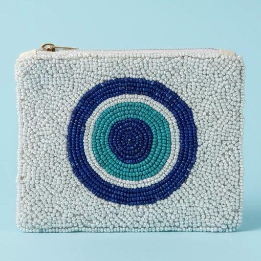 "Occhio di Mare Pouch"  Soft Shades of strong protection.  Inspired by the calming hues of the Mediterranean coastline, the Occhio di Mare beaded pouch blends serenity, symbolism, and Italian charm into a stunning everyday accessory. Hand-crafted with thousands of icy white, sea-blue, and deep navy beads, this pouch features a minimalist evil-eye design that represents clarity, protection, and peaceful energy. Its soft palette makes it effortlessly chic, pairing beautifully with both casual and elegant looks. Fully lined with soft interior fabric, and zip closure with gold-toned hardware. Dimensions: 5" x 4" Perfect as a jewelry pouch, or coin purse, this artisanal piece embodies craftsmanship and meaning. Every bead reflects light, symbolizing resilience, clarity, and confidence.