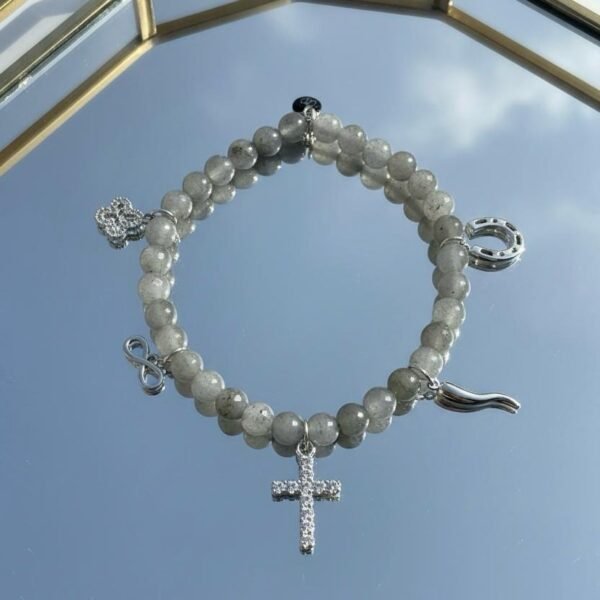 "Raffaella Fortunata Bracelet" Faith, Family & a Little Italian Luck. The Raffaella Fortunata Bracelet is a meaningful blend of faith, family, and timeless Italian luck. Designed with smooth labradorite beads—known for grounding energy, intuition, and protection—this bracelet carries a powerful story in every detail. Each charm holds a piece of tradition and purpose: • A crystal cross, symbolizing unwavering faith and guidance. • An infinity charm, representing eternal love and family bonds. • A horseshoe, the classic Italian emblem of good fortune. • A heart, celebrating the love we give and receive. • The Italian corno, worn for protection and to attract blessings. Elegant, symbolic, and crafted to inspire, the Raffaella Fortunata Bracelet is more than an accessory—it’s a daily reminder that faith anchors us, family lifts us, and luck follows those with strong hearts.