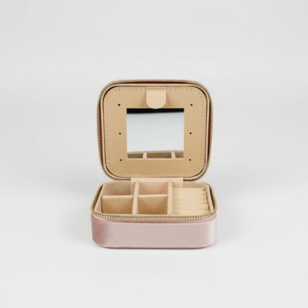 Grazia da Viaggio Organizer  “Elegance that travels with you.” Meet Grazia da Viaggio Organizer, your new must-have travel companion for keeping jewelry beautifully organized wherever life takes you. Crafted in soft blush velvet with a luxe satin finish, this compact organizer opens to reveal a smart, multi-section interior: divided compartments for earrings and pendants, cushioned ring slots, and a built-in mirror for effortless touch-ups on the go. The secure zip-around closure protects your favorite pieces from tangles and scratches, while the lightweight design makes it perfect for handbags, carry-ons, gym bags, or weekend trips. Practical, pretty, and travel-ready — Grazia da Viaggio Organizer brings effortless elegance to every journey. Dimensions: 3.93" × 1.96" Features: Ring rolls, earrings slots, multi-use open compartments, built-in mirror, secure zipper