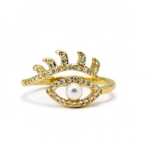 "Occhio di Perla" A watchful eye, crowned with elegance. The Occhio di Perla Ring is a striking fusion of symbolism and sophistication. Crafted in luminous gold plating, this captivating design features an eye-shaped silhouette lined with sparkling pavé crystals, crowned by delicate lashes that shimmer with light. At the center rests a radiant pearl, symbolizing wisdom, clarity, and protection. Inspired by the ancient talisman of the “all-seeing eye,” this ring offers both fashion-forward appeal and a touch of spiritual meaning—perfect for those who embrace bold style with intention. Its adjustable band ensures a comfortable fit, making it as versatile as it is stunning. Whether worn as a statement piece or stacked with other Bella Pia favorites, the Occhio di Perla embodies protection, power, and timeless beauty.